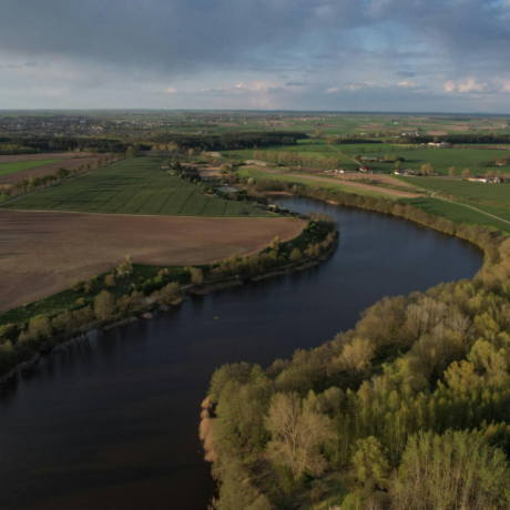 Image of farmland, with a river going through the middle and houses in the distance